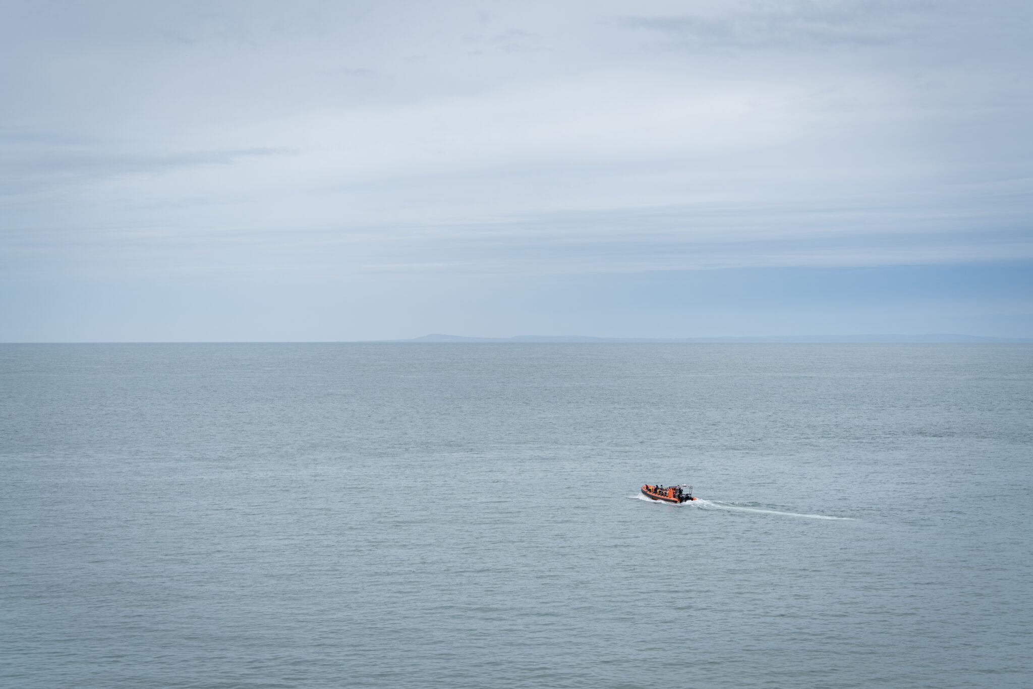 A single boat is travelling on the sea towards the horizon