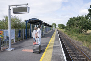 A man waits at a train station holding a suitcase