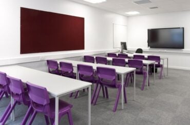 Purple chairs tucked in under white desks in a classroom setting